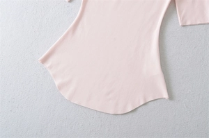 Detail shot of a light pink top showing curved hemline and neat stitching quality