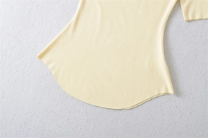 Detailed view of the curved hem and stitching on a light yellow cotton t-shirt