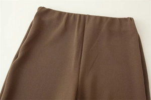 Dettaglio dei pantaloni marroni a vita alta con tessuto in crepe strutturato