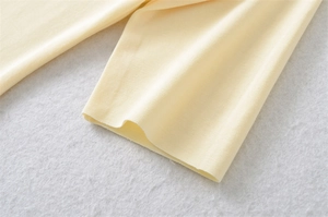 Macro shot of pale yellow ribbed knit fabric texture on women's cotton t-shirt