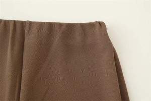 Dettaglio del girovita in tessuto crêpe marrone con trama fine e fascia elastica in vita
