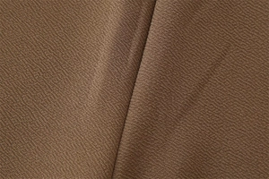 Vista macro del tessuto crepe marrone che mostra la trama a maglia fitta e grana fine