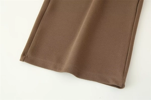 Dettaglio dell'orlo dei pantaloni marroni in crepe testurizzato che mostra la qualità del tessuto