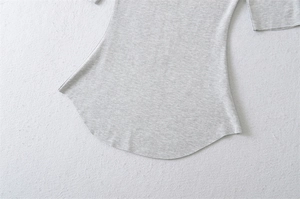 Detail view of light grey knit fabric texture with a curved hem design and smooth stitching