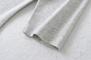 Close-up of premium light grey cotton knit texture with detailed sleeve hem stitching