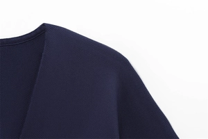 Détail de maille bleu marine à col en V montrant la texture fine et les finitions