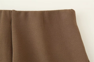Dettaglio macro del tessuto marrone scuro con trama increspata fine e drappeggio pregiato