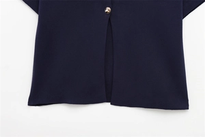 Gros plan détaillé sur la maille bleu foncé avec bouton doré et fente centrale élégante
