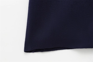 Gros plan sur la texture de maille fine et l'ourlet plat du pull bleu marine à manches courtes