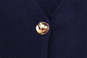 Vue détaillée du tricot bleu marine avec un bouton métallique doré au design moderne