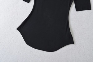 Detail of black fitted top featuring a tapered waist and smooth curved hemline texture
