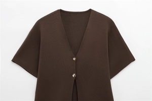 Détail d'un cardigan en maille café à manches courtes avec deux boutons dorés