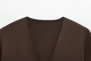Gros plan sur le col en V et la texture en maille fine de ce pull à manches courtes marron foncé