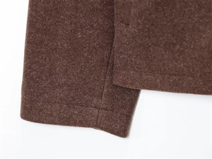 Dettaglio della giacca in lana marrone con trama premium e cuciture precise sull'orlo