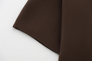Détail de la texture du tissu en maille fine marron foncé sur le pull à manches courtes