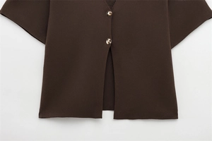 Gros plan d'un gilet en tricot marron foncé avec deux boutons dorés et texture fine