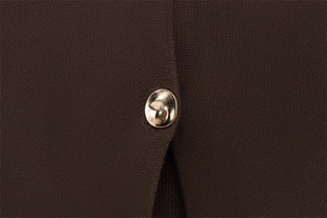 Vue détaillée du tricot marron foncé avec un bouton métallique doré en forme de demi-sphère