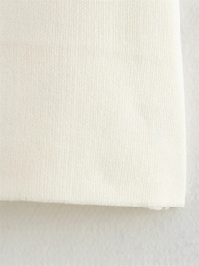 Gros plan sur un tissu en maille beige montrant la texture douce et les détails