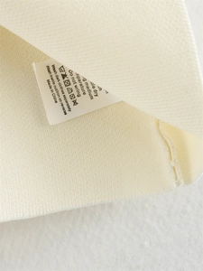 Vue détaillée de l'étiquette d'entretien et de la texture d'un pull en maille beige