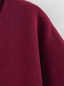 Gros plan détaillé sur la maille fine de couleur bordeaux et les finitions de ce pull à manches