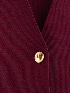 Détail de la maille bordeaux et du bouton en métal doré sur le haut avec col en V profond