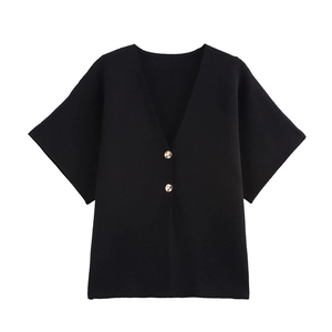 Détail d'un cardigan noir en maille à col en V avec deux boutons dorés métalliques
