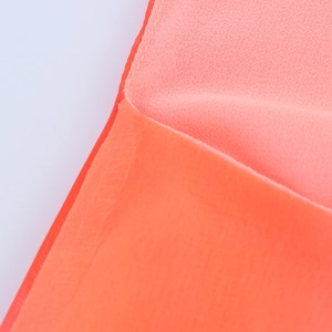 Detail von korallenrotem Chiffonstoff mit sauberen Kantennähten und halbtransparenter Textur