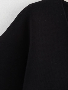 Détail montrant la texture en maille fine et les coutures d'un cardigan noir à manches courtes