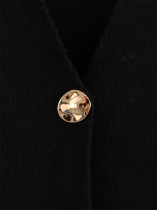 Gros plan d'un bouton doré texturé sur un cardigan noir à manches courtes