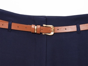 Dettaglio dei pantaloni blu scuro con cintura in pelle marrone e fibbia in oro