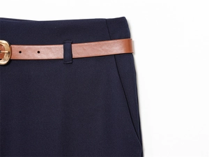 Dettaglio dei pantaloni blu navy con cintura marrone e fibbia in metallo dorato in vita
