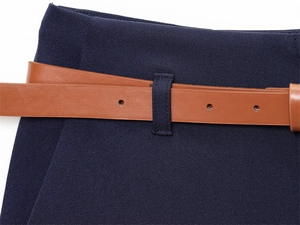 Dettaglio dei pantaloni blu navy con trama in twill granuloso e cintura in pelle marrone