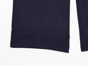 Dettaglio dei pantaloni blu scuro con cuciture precise sull'orlo e tessuto morbido