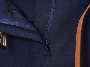 Dettaglio di pantaloni blu scuro con cerniera e sottile cintura marrone con fibbia dorata
