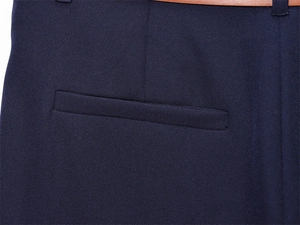 Dettaglio dei pantaloni blu navy con tasca a filo posteriore e sottile cintura marrone