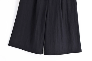 Detailed close-up of high-quality black wide-leg trousers with textured fabric and stitching