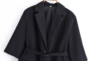 Detail of a black blazer with notched lapels, single-breasted buttons and matching belt