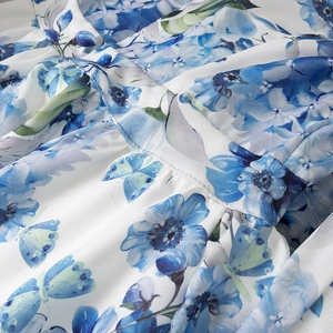 Detalle del tejido de vestido de lino con estampado floral y patrón de mariposas azul