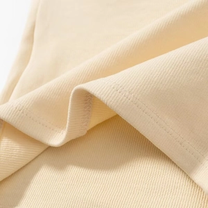 Detailed close-up of beige ribbed knit fabric showing the fine texture and hem stitching