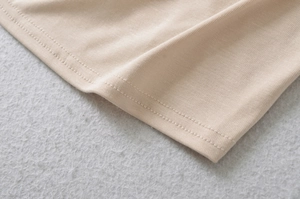 Detailaufnahme der feinen Nähte und der weichen Strickstruktur eines beigen Oberteils