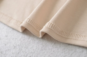 Detailansicht der Overlock-Naht am Saum eines weichen beigen Strickoberteils für Damen