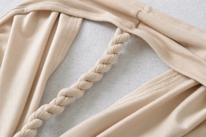 Detailaufnahme der geflochtenen Träger an einem champagnerfarbenen Strickoberteil