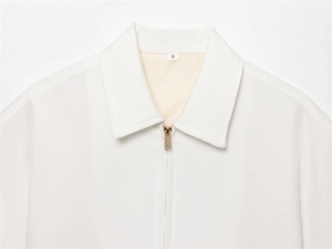 Detail of the white jacket collar with size S label and gold metal zipper puller