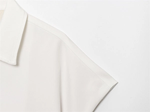 Close-up detail of the lapel collar and shoulder stitching on this white short sleeve jacket