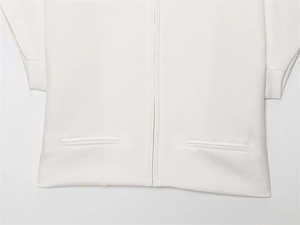 Detail of white short jacket showing metal zipper and symmetrical side welt pockets