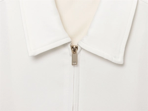 Close-up of white lapel collar featuring a premium light gold metallic zipper detail
