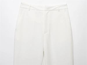 Detail shot of white high-waisted trousers featuring belt loops and a hidden closure