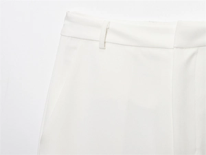 Detail view of white trouser waistband showing fabric texture, belt loop, and pocket edge