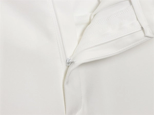 Close-up of white straight-leg pants showing the seamless invisible zipper and fabric texture