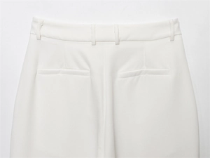 Close-up of high-waist white trousers featuring belt loops and faux back pockets